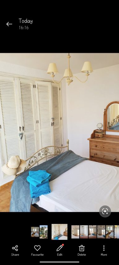 A neatly arranged bedroom with a bed, wardrobe, mirror, and blue towels.